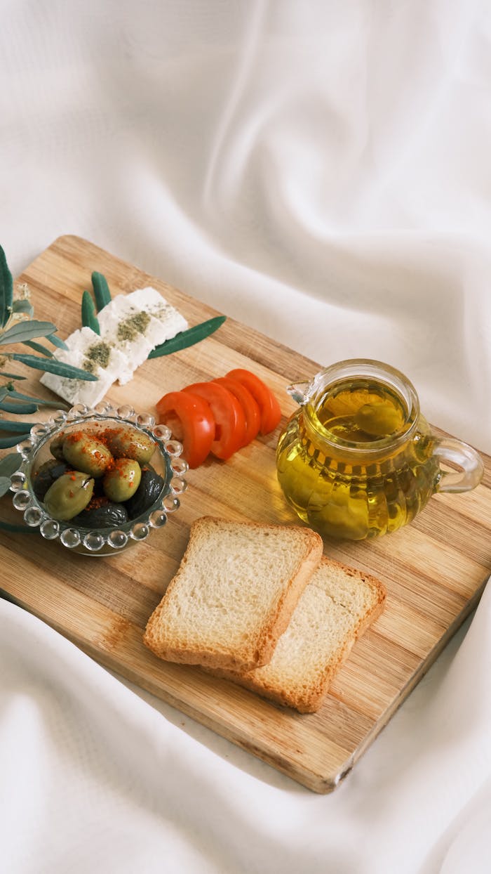 Mastering the First Impression: Your intriguing post title goes here A still life of Mediterranean ingredients on a wooden board, including olive oil, bread, and vegetables.